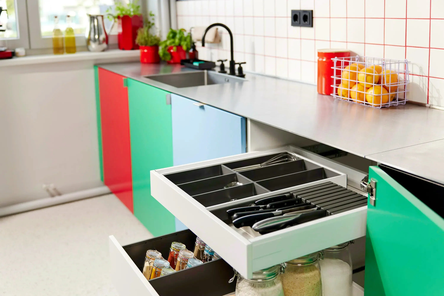 Moderne Küche mit bunten Schrankfronten, Besteckkasten, Messerblock und Gewürzhalter in Schublade