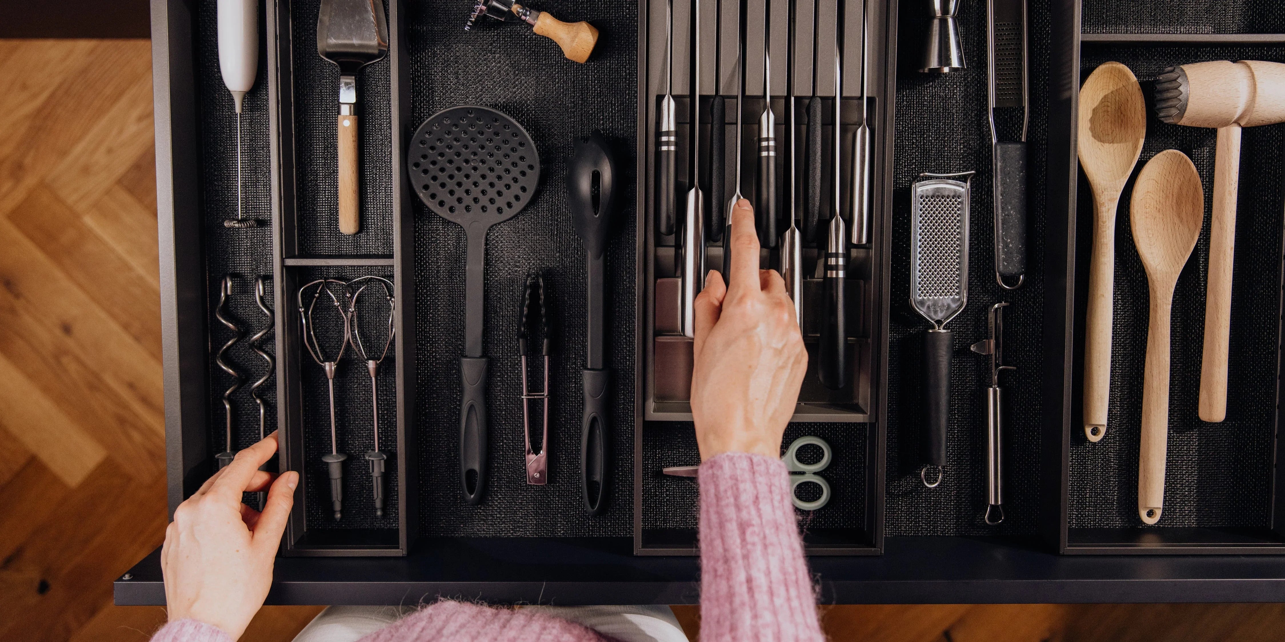Organisierter Besteckkasten mit Küchenhelfern, Messern und Holzbesteck in Küchenschublade